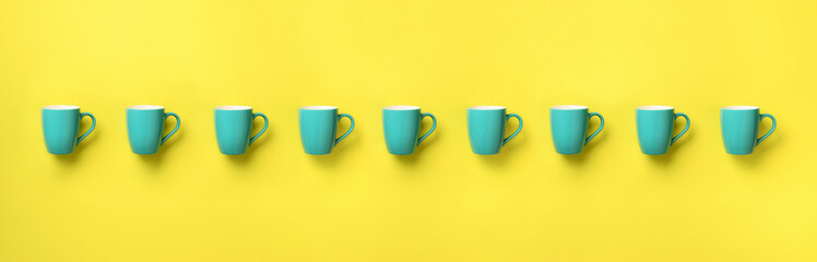 Pattern from blue cups over yellow background. Banner. Birthday party celebration, baby shower concept. Punchy pastel colors. Minimalist style design