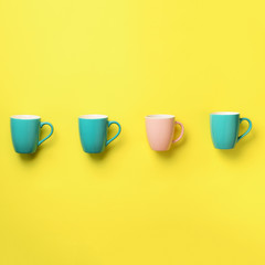 Pattern from blue and pink cups over yellow background. Square crop. Birthday party celebration, baby shower concept. Punchy pastel colors. Minimalist style design