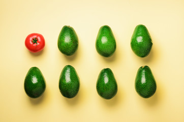 Green sliced avocado and red tomato on blue and yellow background. Top view. Pop art design, creative summer food concept. Minimal flat lay style.