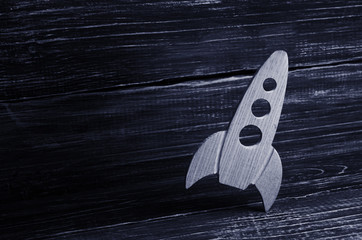 Wooden space rocket in retro style is on a dark wooden background. The space industry, the development of technology and the conquest of space. Creative thinking and business concept.