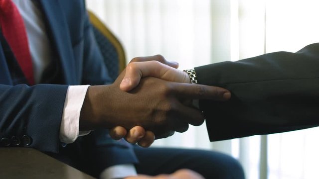 Handshake of two multiracial men in suits as sign of trusted partnership