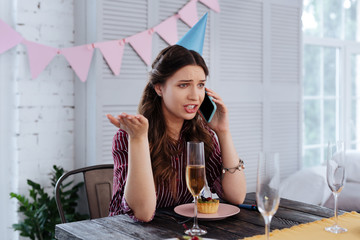 Shouting at boyfriend. Woman wearing striped blouse shouting at her boyfriend sitting at the table