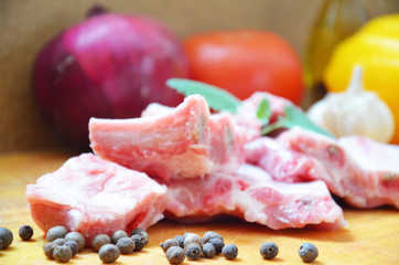 Raw uncooked pork ribs on a paper on dark brown wooden background. Ingredients for meat raw pork ribs sage, thyme, rosemary, pepper, basil, salt.