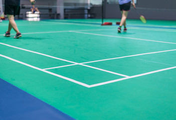 Fototapeta na wymiar badminton court with blurred badminton player holding racket indoor court