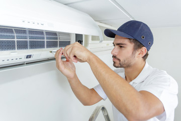 portrait of mid-adult male technician repairing air conditioner