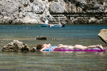 Beautiful girls lying on rubber mats in Anthony Quinn Bay, Rhodes Island, Greece