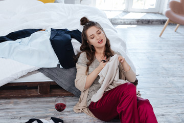Ex wife. Ex wife sitting on the floor near bed with scissors while cutting many clothes after...