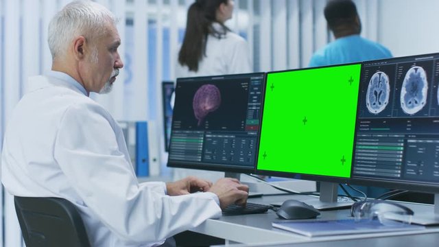 Scientist Working with Mock-up Green Screen and CT Brain Scan Images on a Personal Computer in Laboratory.  Shot on RED EPIC-W 8K Helium Cinema Camera.