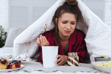 Ice cream. Stressed emotional woman eating big ice cream and crying after breakup with her handsome...