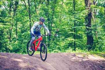 Obraz premium A cyclist in a helmet descends from the mountain on an orange bicycle