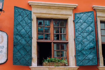 An open rustic wooden window of  house against a background of an orange wall.