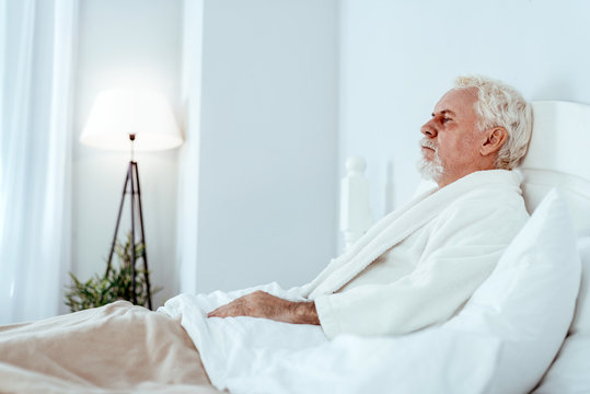 Under The Weather. Pessimistic Senior Man Lying In Bed And Posing In Profile