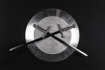 shiny metal shield and sword on a black isolated background