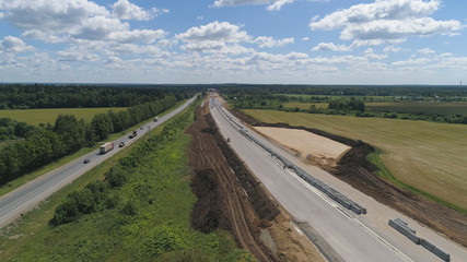 Construction of toll roads in rural areas. Aerial view construction of a new highway next to the old highway.