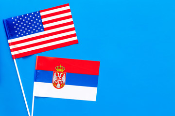 USA-Serbia relations. Country cooperation. American and Serbian flags on blue background top view copy space