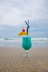 Blue coctail in the glass on the sea background