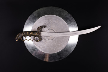 shiny metal shield and sword on a black isolated background