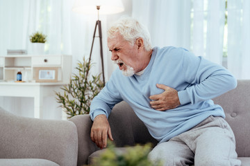 Light heart attack. Restless senior man touching chest and shouting