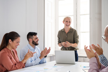 Group of office colleagues laughing and clapping