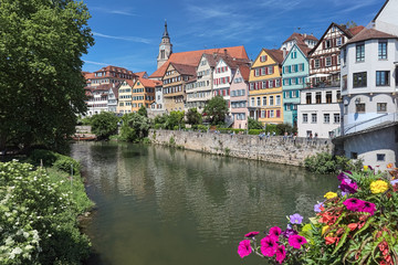 Picturesque view of the historical houses across the riverside of Neckar in the university town of Tubingen, Germany. View from bridge decorated with multicolored natural flowers.