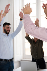 Corporate group celebrating with raised hands