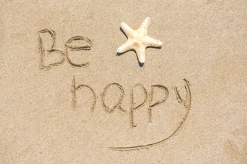 Fototapeta na wymiar Be happy written on white sand, beach background with copy space 