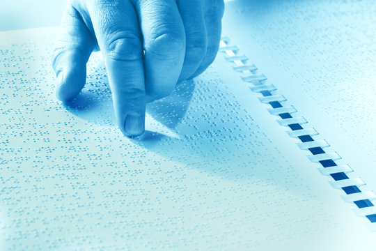 Hand of a blind person reading some braille text touching the relief. Duotone