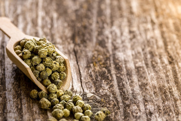 Green peppercorns  in a spoon on wooden table