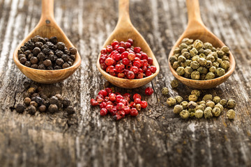     Different pepper in a wooden spoons on wooden table.
