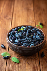Fototapeta na wymiar Honeysuckle berries or Lonicera caerulea in ceramic bowl on wooden background