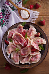 Dumplings, filled with strawberries, berries. Pierogi, varenyky, vareniki, pyrohy - dumplings with filling, popular dish in many countries. overhead, vertical