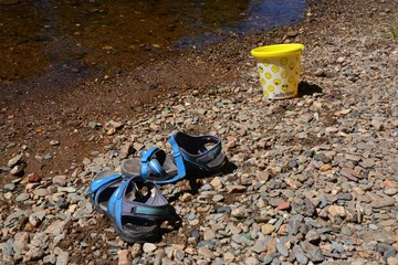 Eimer und Schuhe am Flussufer