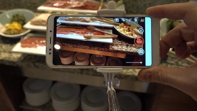 Trend blogger makes photo of meat delicacies on a cell phone.