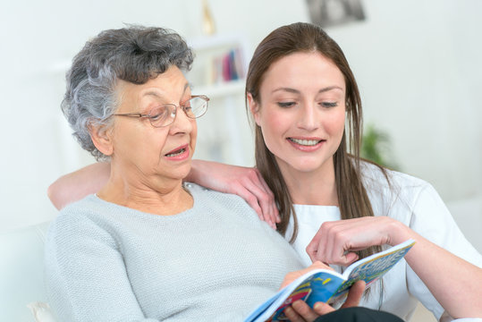 woman and senior woman with book at home