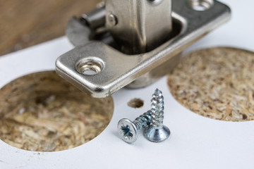 Mounting hinges for chipboard furniture. Joinery accessories used when assembling kitchen furniture.