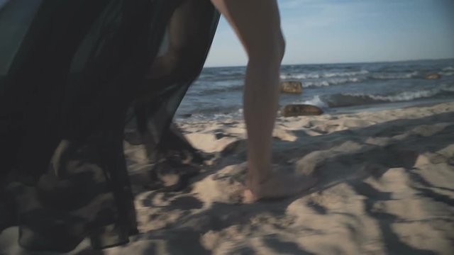 Girl in black dresses runs along the beach.