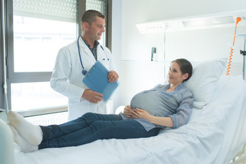Fototapeta premium doctor talking to pregnant woman in hospital bed