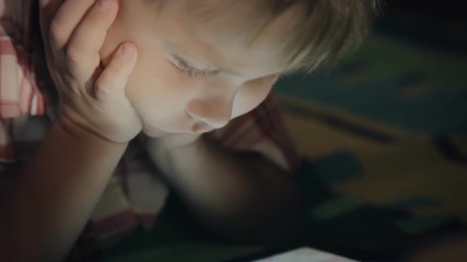 Boy looking at tablet computer at night