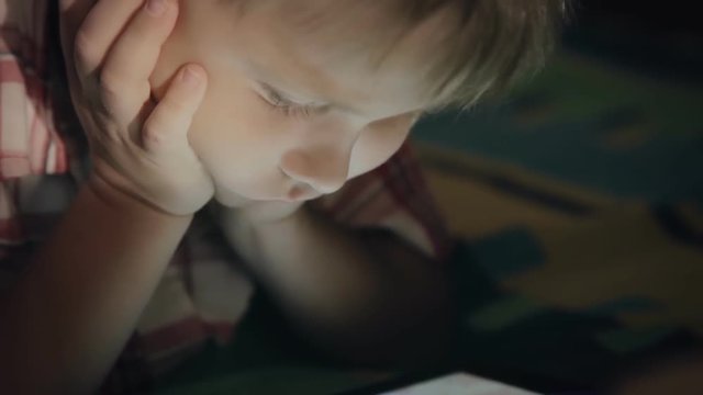 Boy looking at tablet computer at night