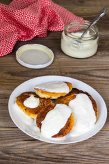Pancakes with cottage cheese, sour cream in a white plate