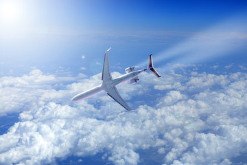 Samolot odrzutowy nad chmurami schodzi do lądowania w promieniach słońca. - obrazy, fototapety, plakaty