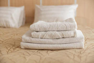 Fototapeta na wymiar Stack of white hotel towel on bed in hotel. Soft focus.