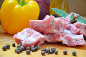 Raw uncooked pork ribs on a paper on dark brown wooden background. Ingredients for meat raw pork ribs sage, thyme, rosemary, pepper, basil, salt.