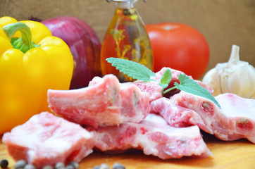 Raw uncooked pork ribs on a paper on dark brown wooden background. Ingredients for meat raw pork ribs sage, thyme, rosemary, pepper, basil, salt.