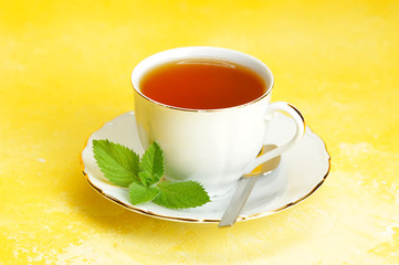 Cup of tea and saucer with mint leaf