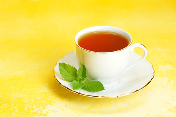 Cup of tea and saucer with mint leaf