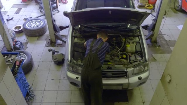 Auto mechanic repairs the car at the service station. Top view