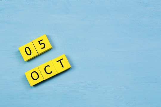 OCT 5, yellow cube calendar on blue wooden surface with copy space