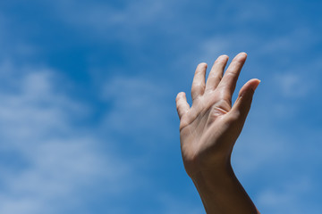 Woman raise hand up showing the five fingers on blue sky with white cloud background