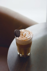 Milkshake macchiato overshake with chocolate and cookies. Cappuccino with whipped creamand caramel on a wooden table in a coffee house. Trendy food concept.